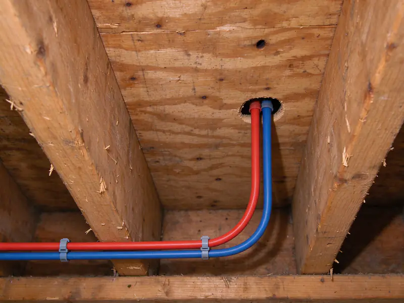 The same crawl space with new red and blue PEX lines strapped to the joists